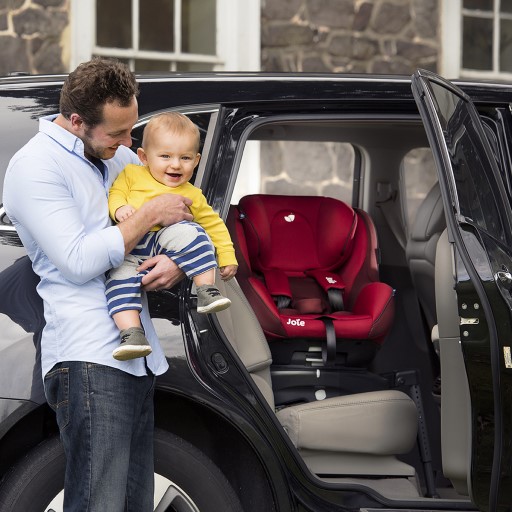 Jeune papa installant son bébé dans un siège auto pivotant, face portière